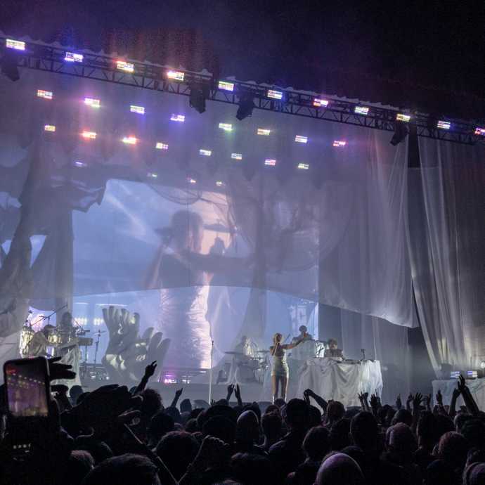 Robyn wearing a white dress and arm in the air